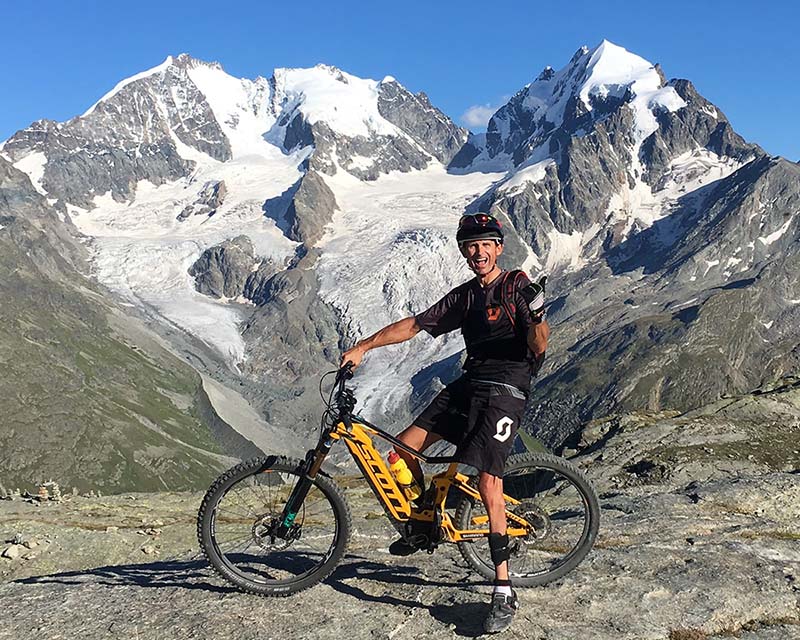 Michael Teuber auf einer Ausfahrt in den Bergen mit seinem gelben Scott E-Mountainbike mit SHIMANO Antrieb. 